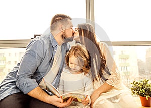 happy family reading a book to her daughter.