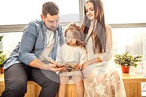 Happy family reading a book to her daughter.