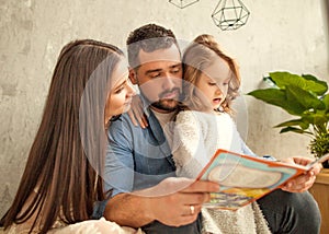 Happy family reading a book to her daughter. Mothers Day