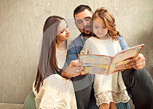 Happy family reading a book to her daughter. Mothers Day.