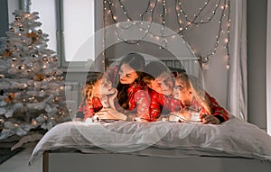 A happy family in red Christmas pajamas are lying in a cozy bed in the morning. new year