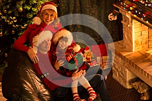 Happy family in red hats with gifts sitting at