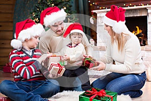Happy family in red hats with gifts sitting at