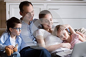 Happy family relax in living room watching cartoons on laptop photo