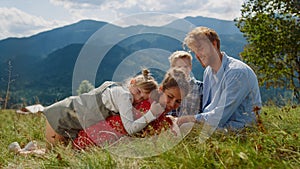 Happy family relaxing grass at sunny day. Couple with kids lying green meadow.