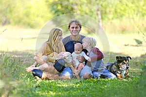 Happy Family Relaxing Outside with Dog