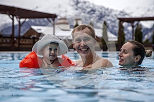 Happy family relaxing in the spa center with a child swims in the pool