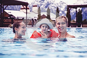 Happy family relaxing in the spa center with a child swims in the pool