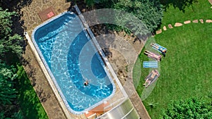 Happy family relaxing by swimming pool, aerial drone view from above of parents and kids have fun on vacation, family weekend