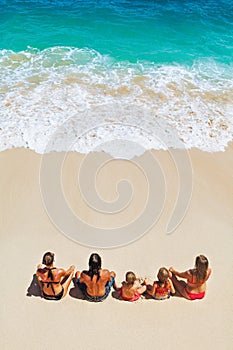 Happy family relaxing on white sand sea beach