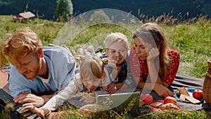Happy family rest tablet on green meadow sunny day close up. Summer holiday.