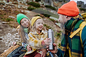 Happy family resting, having snack during hiking together in autumn mountains.