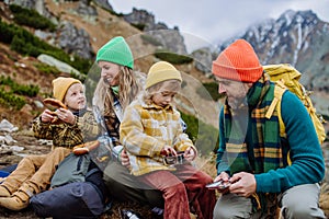 Happy family resting, having snack during hiking together in autumn mountains.