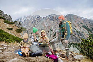 Happy family resting, having snack during hiking together in autumn mountains.