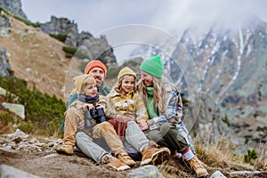Happy family resting during long hike in autumn mountains.
