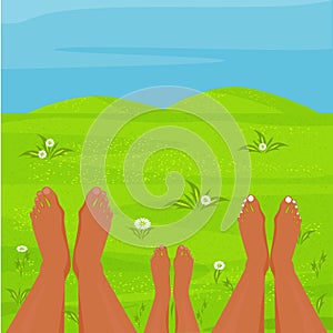 A happy family is resting in a meadow. Parents and child are lying barefoot on the grass.