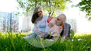 Happy family is resting on nature. Parents play with a small child daughter in a park in the summer at sunset.