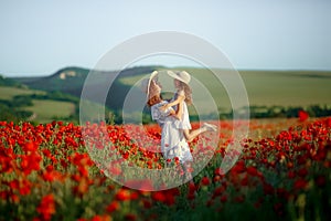 A Happy family resting on the poppy field. Mother playing with her child in poppy field.