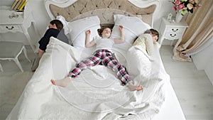 Happy Family are Resting on the White Bed. Portrait of Asleep Mother, Father and Little Daughter in Pajamas in the
