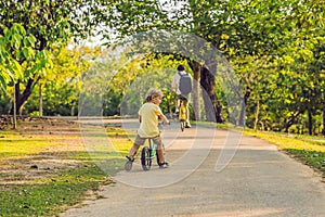 Happy family is riding bikes outdoors and smiling. Father on a b