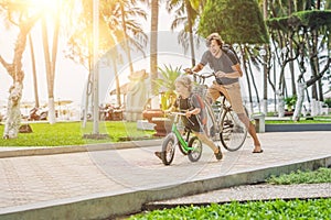 Happy family is riding bikes outdoors and smiling. Father on a b