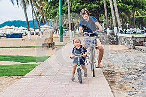 Happy family is riding bikes outdoors and smiling. Father on a b
