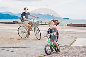 Happy family is riding bikes outdoors and smiling. Father on a b