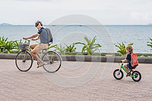 Happy family is riding bikes outdoors and smiling. Father on a b