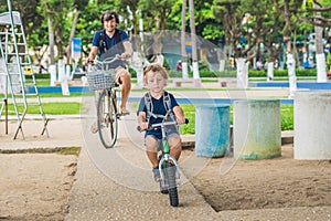 Happy family is riding bikes outdoors and smiling. Father on a b