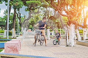 Happy family is riding bikes outdoors and smiling. Father on a b