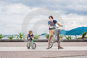 Happy family is riding bikes outdoors and smiling. Father on a b