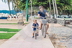 Happy family is riding bikes outdoors and smiling. Father on a b