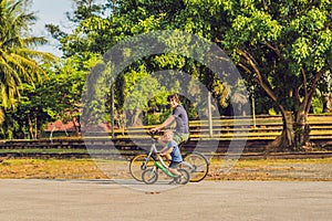 Happy family is riding bikes outdoors and smiling. Father on a bike and son on a balancebike