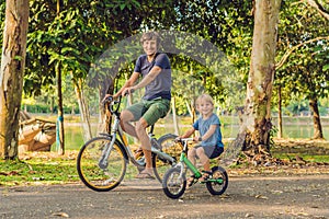 Happy family is riding bikes outdoors and smiling. Father on a bike and son on a balancebike