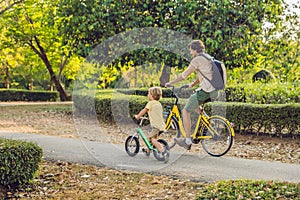 Happy family is riding bikes outdoors and smiling. Father on a bike and son on a balancebike