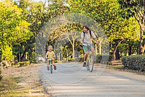 Happy family is riding bikes outdoors and smiling. Father on a bike and son on a balancebike