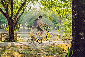 Happy family is riding bikes outdoors and smiling. Father on a bike and son on a balancebike