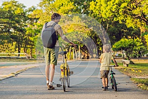 Happy family is riding bikes outdoors and smiling. Father on a bike and son on a balancebike