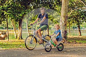 Happy family is riding bikes outdoors and smiling. Father on a bike and son on a balancebike