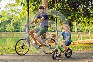 Happy family is riding bikes outdoors and smiling. Father on a bike and son on a balancebike