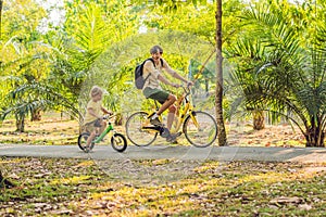 Happy family is riding bikes outdoors and smiling. Father on a bike and son on a balancebike