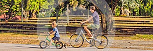 Happy family is riding bikes outdoors and smiling. Father on a bike and son on a balancebike BANNER, long format
