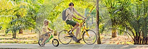 Happy family is riding bikes outdoors and smiling. Father on a bike and son on a balancebike BANNER, long format