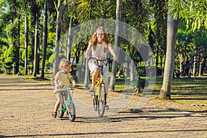 Happy family is riding bikes outdoors and smiling. Mom on a bike