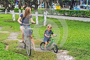 Happy family is riding bikes outdoors and smiling. Mom on a bike