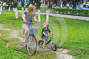 Happy family is riding bikes outdoors and smiling. Mom on a bike