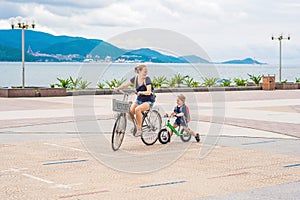Happy family is riding bikes outdoors and smiling. Mom on a bike