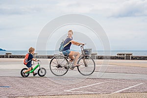 Happy family is riding bikes outdoors and smiling. Mom on a bike