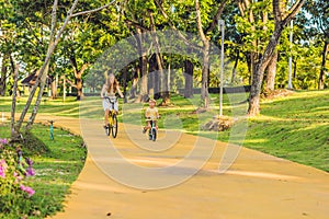 Happy family is riding bikes outdoors and smiling. Mom on a bike and son on a balancebike