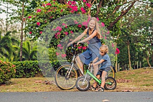 Happy family is riding bikes outdoors and smiling. Mom on a bike and son on a balancebike